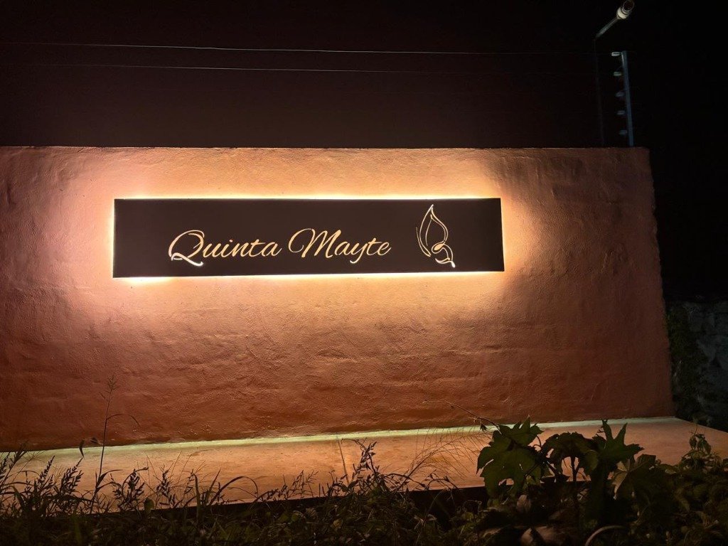 Letrero arquitectónico en placa de acero con halo nocturno cálido en fachada